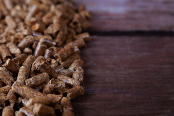 Obraz premium Wood pellets appearing as a renewable energy source for heating, showing biomass fuel on a dark wood background