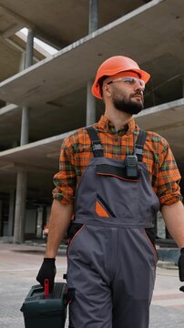 Construction worker walking on building site with toolbox