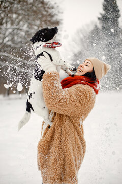 Woman standing at winter park and holding a black dog