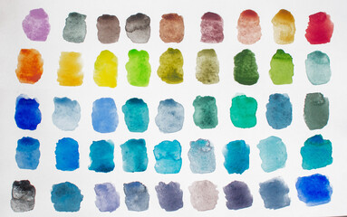 A variety of watercolor palettes of warm  and cool shades on a white paper background.