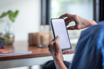 Close-up of a person using a smartphone indoors, focusing on hands holding the device with a blurred background, representing modern technology and communication, in landscape