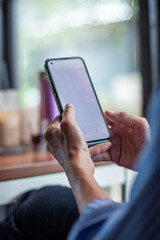 Close-up of a person using a smartphone indoors near a table with drinks, showing everyday digital lifestyle and modern communication habits, in portrait