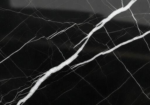 Dramatic luxury texture of black marble featuring a thick, bold white vein contrasted with hairline fissures
