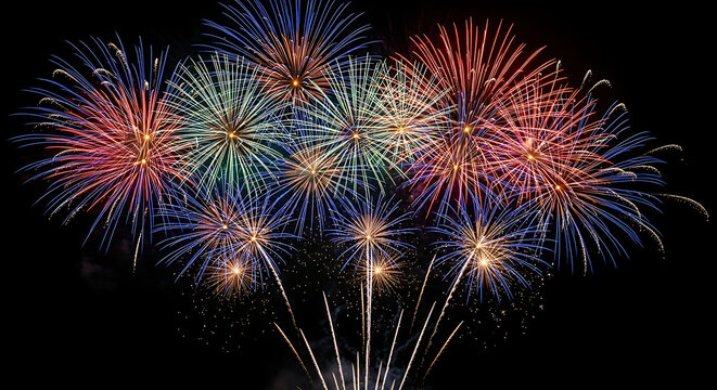 A vibrant, long-exposure photograph capturing multiple bursts of red, blue, and green fireworks against a dark night sky