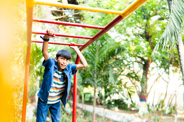 Happy preteen boy playing on monkey bars at park