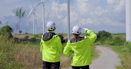 Caucasian engineers in reflective jacket and helmet review turbine operation at wind farm point toward horizon coordinate power check ensure safety advance renewable clean electricity project teamwork