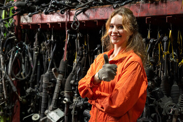Female technician worker standing and smile to the camera in garage scrap yard warehouse.