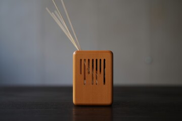 Small orange diffuser with white reeds on a dark surface