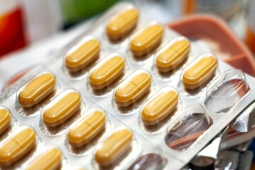 Blister pack with large yellow oblong tablets on an adult's medication table, partially used