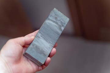 Male hand holding a well-used sharpening steel rod showing signs of frequent use