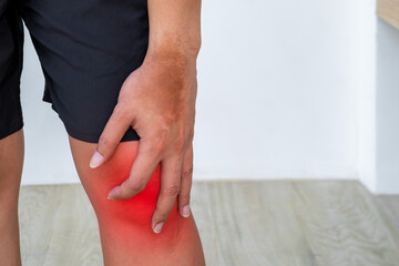 Athlete clutching inflamed knee after workout. Red pain zone signals joint injury. Copy space for physiotherapy or orthopedic care promotions.