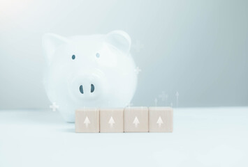 A white piggy bank with wooden blocks featuring upward arrows symbolizes financial growth, savings strategy, investment planning, and long-term wealth management in a clean minimalist concept.