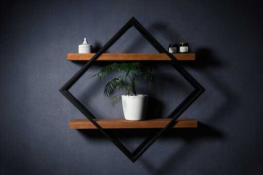 Modern wall shelf with geometric design. Decorative wooden and metal shelf on a dark wall. Designer diamond-shaped wall shelf in loft style