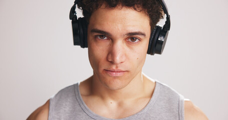 Portrait, athlete and man with headphones in studio for fitness, listening to music and podcast. Male person, streaming song and playlist audio for exercise, training motivation and white background