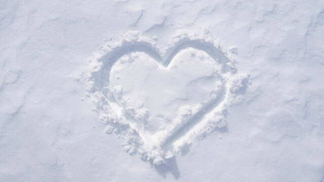 Snow heart on a white winter background. Frosty heart shape in snowy field. Romantic snow heart drawing outdoors. Winter love symbol on frozen surface. Snowflake heart detail. Snow love.