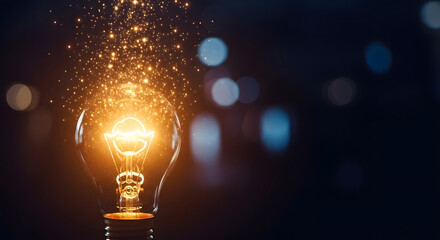 Bright incandescent lightbulb exploding with golden sparks and bokeh lights at night