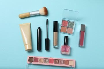 Obraz premium Beauty products on blue background. Cosmetic palette, brushes, cream and lipsticks. Top view.