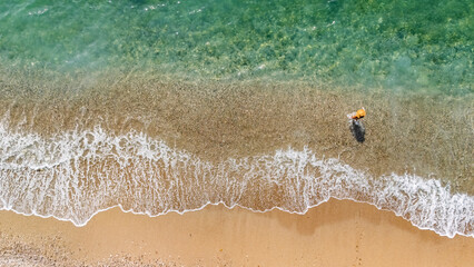 Aerial drone view of sandy beach and turquoise sea waves with people sunbathing, swimming and relaxing, holiday vacation concept, Antalya Konyaalti beach, Turkey