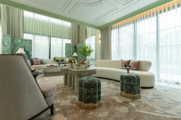 Interior of a luxurious sitting room with bay window sofas and coffee table. White and green tone of vast luxury living room.
