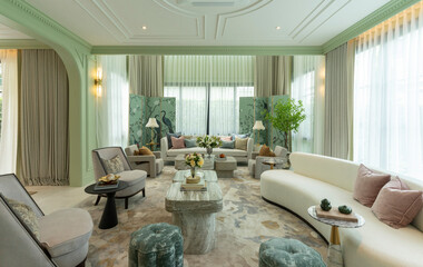 Interior of a luxurious sitting room with bay window sofas and coffee table. White and green tone of vast luxury living room.
