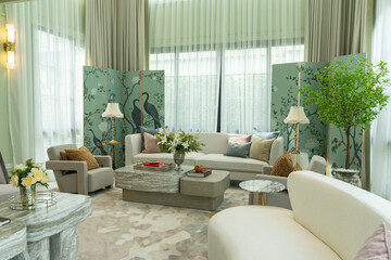 Interior of a luxurious sitting room with bay window sofas and coffee table. White and green tone of vast luxury living room.
