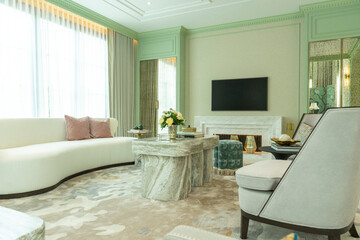 Interior of a luxurious sitting room with bay window sofas and coffee table. White and green tone of vast luxury living room.
