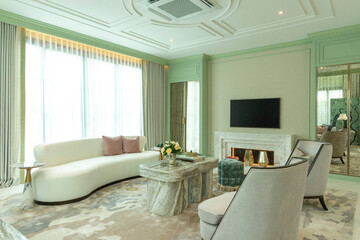 Interior of a luxurious sitting room with bay window sofas and coffee table. White and green tone of vast luxury living room.
