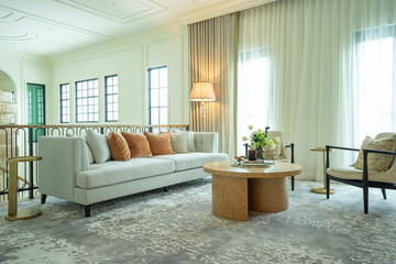 Interior of a luxurious sitting room with bay window sofas and coffee table. White and green tone of vast luxury living room.
