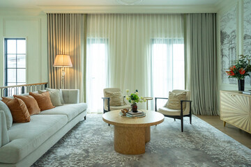 Interior of a luxurious sitting room with bay window sofas and coffee table. White and green tone of vast luxury living room.
