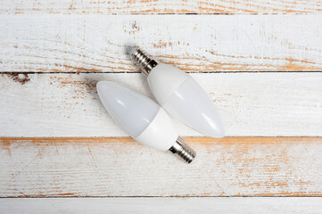 Two LED lamps with E14 sockets lying on a wooden surface.