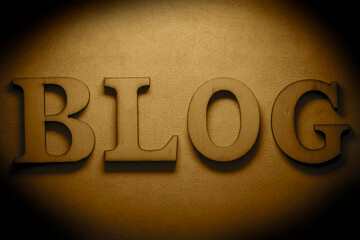 Word blog made with wood letters on a brown grunge paper background backdrop, with a black border.