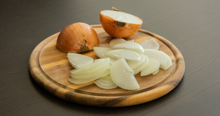 slicing onion on wooden cutting board close up