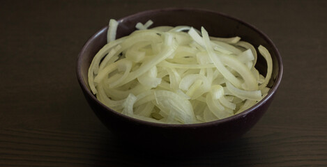 onion slices in dark bowl on dark table