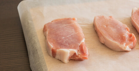 fresh raw pork chops on white parchment paper