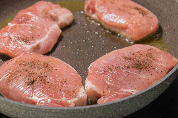 seasoned raw pork chops in pan ready to cook