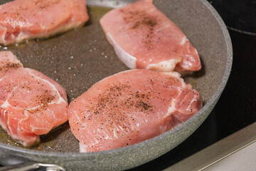 seasoned raw pork chops in pan ready to cook