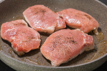 seasoned raw pork chops in pan ready to cook