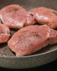 seasoned raw pork chops in pan ready to cook