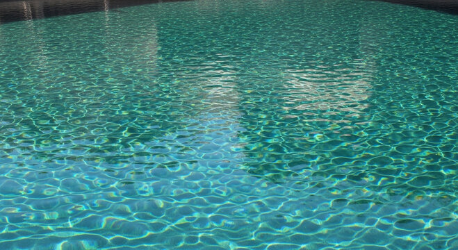 Clear turquoise water in a swimming pool with sunlight reflections