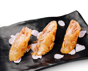 Savory spring rolls with delicate almond slices on a black plate