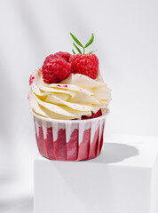 Delicious raspberry cupcake topped with cream on a white background
