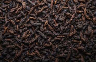 Dried black tea leaves form a rich dark texture. These aromatic long tea leaves are unfurled, ready for brewing a hot drink. Loose tea composition offers natural ingredients for herbal infusion.