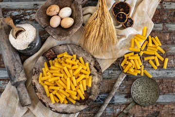 Different types of uncooked pasta on rustic wooden table, in the spoons, cutting board and bowls 