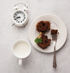 healthy evening snack with milk and banana bread and alarm, top view