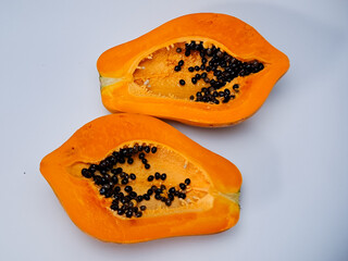 Vibrant still life featuring two halves of a papaya, showcasing the contrasting colors and textures.