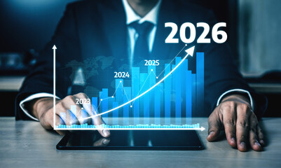 A businessman is analyzing financial growth trends on a digital tablet that displays projected figures from 2023 to 2026, emphasizing future success. Tessel