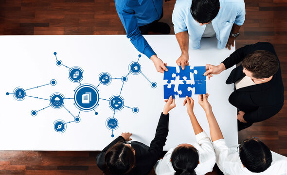 A diverse team engages in a strategic session, collaborating over puzzle pieces on a table. Business concepts are illustrated, showcasing teamwork and innovation in problem-solving. Amity - Powered by Adobe