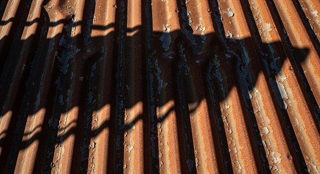 Shadows cast on a corrugated metal surface with peeling paint and rust - Powered by Adobe