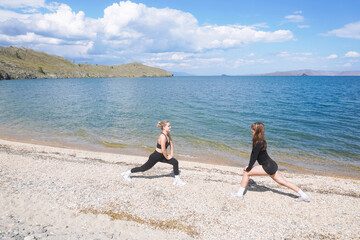 Two individuals training on a beach during a sunny day near the waterline