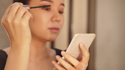 A young woman applies makeup in front of a mirror, focusing on her daily beauty and skincare routine. Elegant and natural look, perfect for beauty, lifestyle, and cosmetic content
